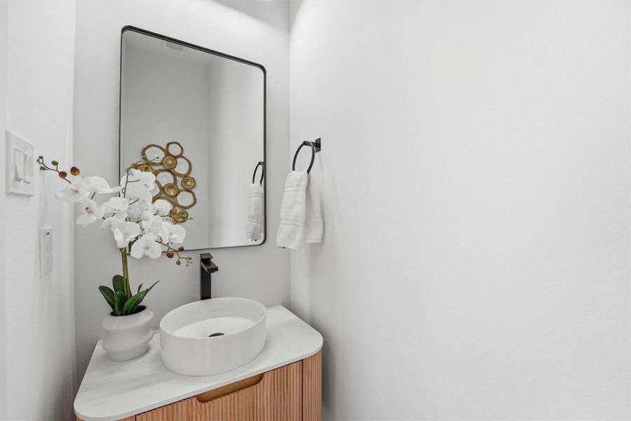 Stylish powder bath featuring a modern floating vanity with vessel sink, quartz countertop, matte black fixtures, and contemporary mirror, creating a sleek and elegant design with a spa-inspired feel.