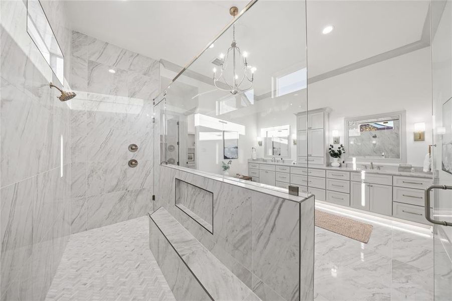 Full bath with two vanities, a marble finish shower, suspended lighting, and light marble finish flooring Full bath with two vanities, a marble finish shower, suspended lighting, and light marble finish flooring