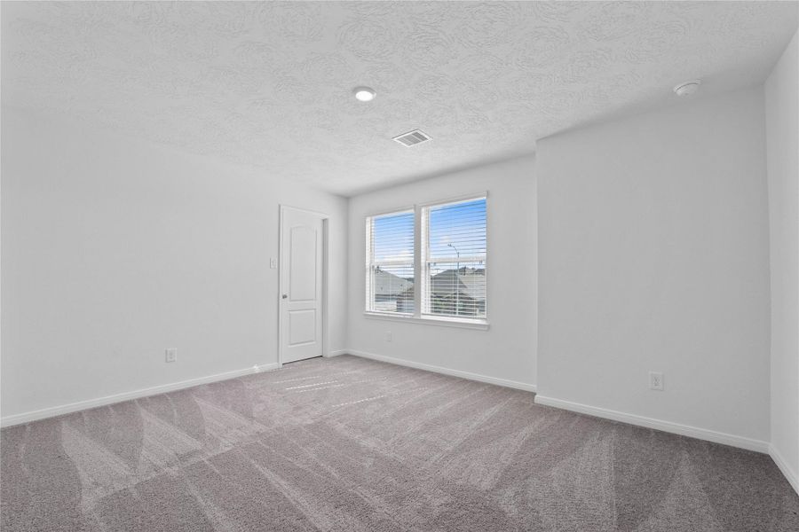 This secondary bedroom offers comfort and style with plush carpeting, neutral paint tones, recessed lighting, large windows with blinds, and a walk-in closet.
