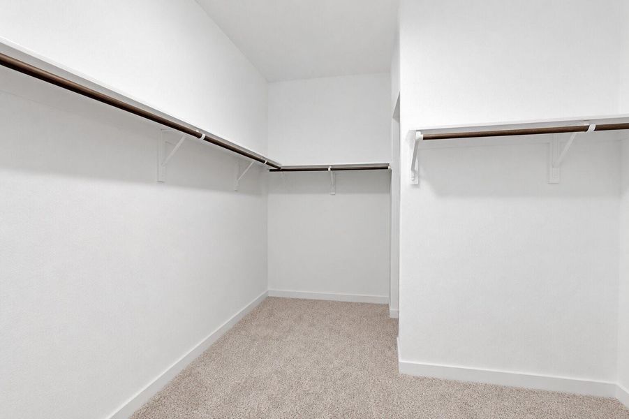 An expansive walk-in closet features thoughtfully designed storage, including generous hanging space, shelving, and ample room for a curated wardrobe.