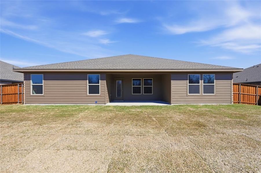 Rear exterior featuring a covered patio, multiple windows, and a wood privacy fence Rear exterior featuring a covered patio, multiple windows, and a wood privacy fence
