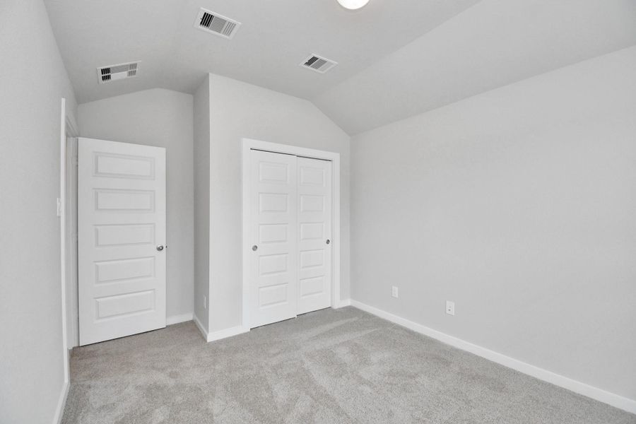 Secondary bedroom features plush carpeting, large windows that let in plenty of natural light, bright paint, and spacious closets.
