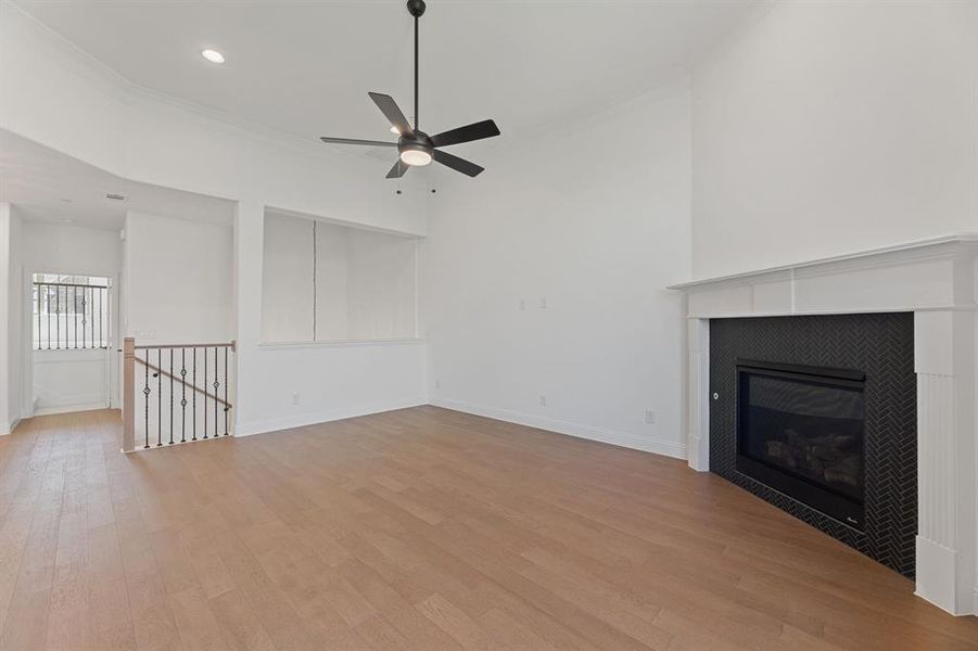 Unfurnished living room with light wood-style floors, ornamental molding, a fireplace, recessed lighting, and ceiling fan Unfurnished living room with light wood-style floors, ornamental molding, a fireplace, recessed lighting, and ceiling fan