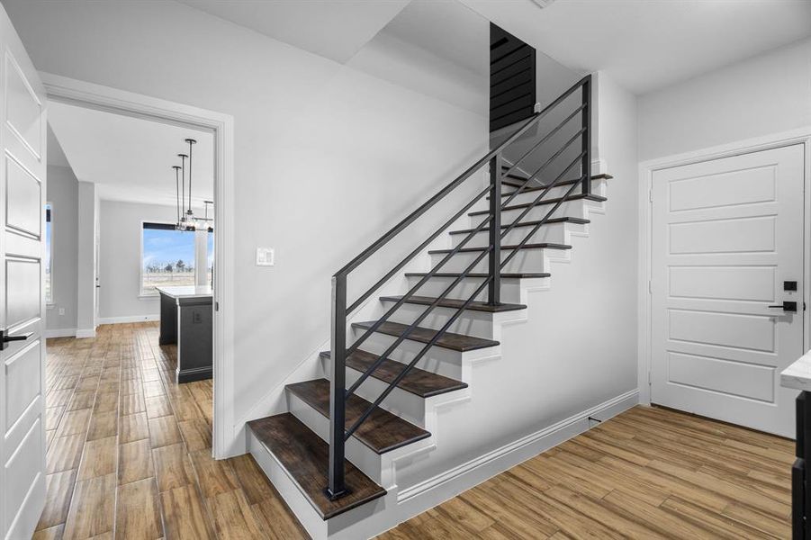 Stairway featuring wood-type flooring and an inviting chandelier