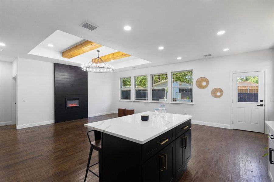 Kitchen featuring dark cabinetry, dark wood finished floors, recessed lighting, a raised ceiling, and light countertops Kitchen featuring dark cabinetry, dark wood finished floors, recessed lighting, a raised ceiling, and light countertops