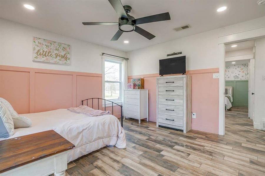 Bedroom featuring a wainscoted wall, light wood-style flooring, a decorative wall, a ceiling fan, and recessed lighting