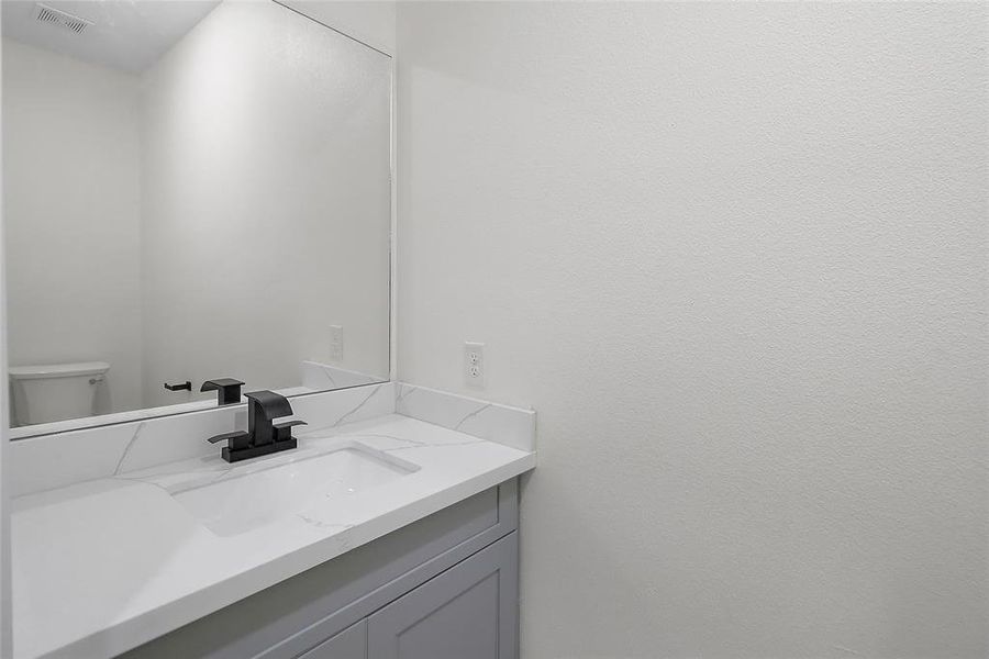 A modern vanity with a contemporary countertop and stylish faucet serves as the focal point, offering convenience for guests to freshen up.