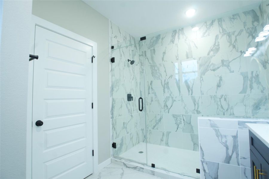 Full bath featuring a shower stall, marble finish floors, and vanity