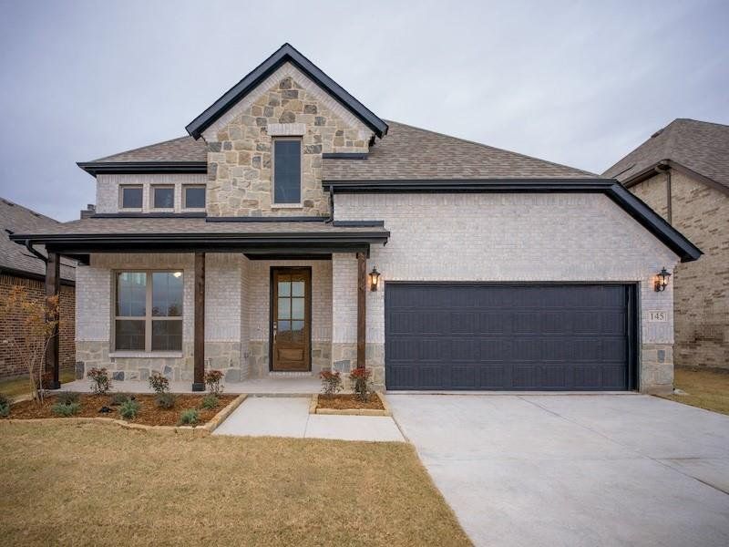 View of front of home featuring a garage, covered porch, and a front lawn