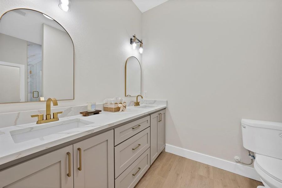 Bathroom with double vanity, light wood finished floors, and a marble finish shower