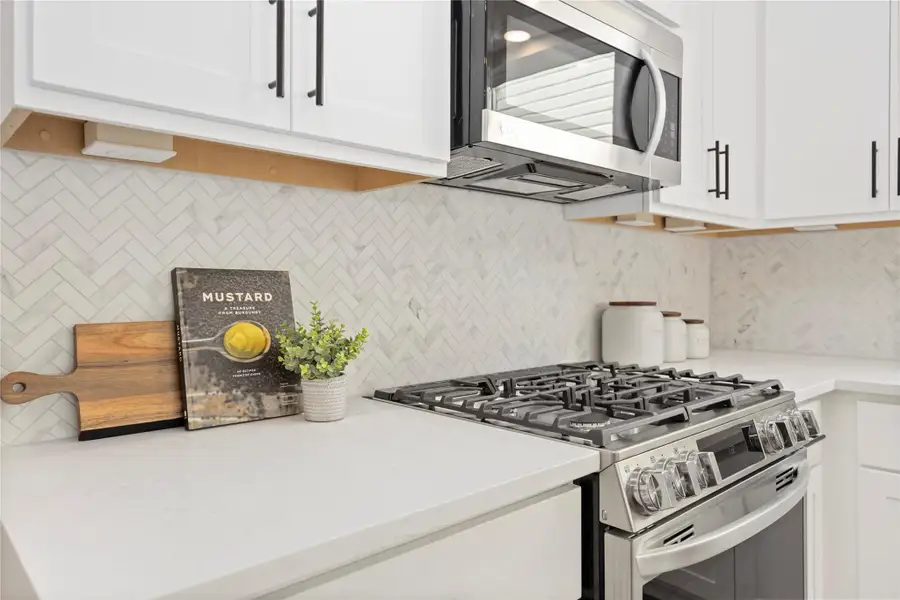 Unleash your culinary brilliance with a five-burner natural gas range, expansive undermount stainless steel sink with a modern gooseneck faucet, framed by ample storage within the island’s embrace.