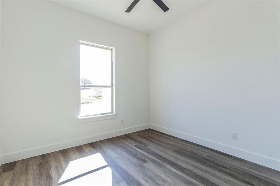 Empty room featuring a healthy amount of sunlight, ceiling fan, and hardwood / wood-style flooring