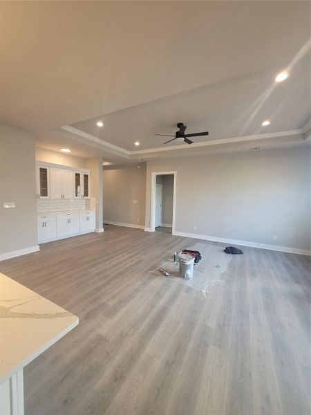 Unfurnished living room with light wood-style flooring, recessed lighting, a ceiling fan, and a tray ceiling