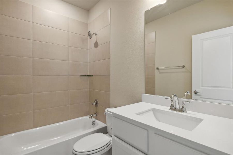 Full bathroom featuring toilet, vanity, and tiled shower / bath