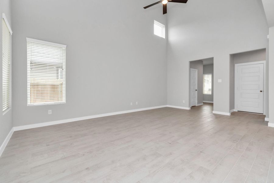 Bring your loved ones and guests together in the inviting living room! Boasting lofty high ceilings, recessed lighting, a stylish ceiling fan, custom paint, stunning flooring, and expansive windows that flood the space with ample natural light all day long. Sample photo of completed home with similar floor plan. Actual colors and selections may vary.