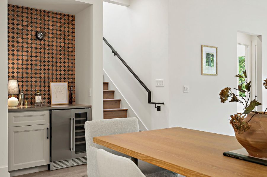 Dining room with beverage cooler, a dry bar, stairs, and light wood-style floors