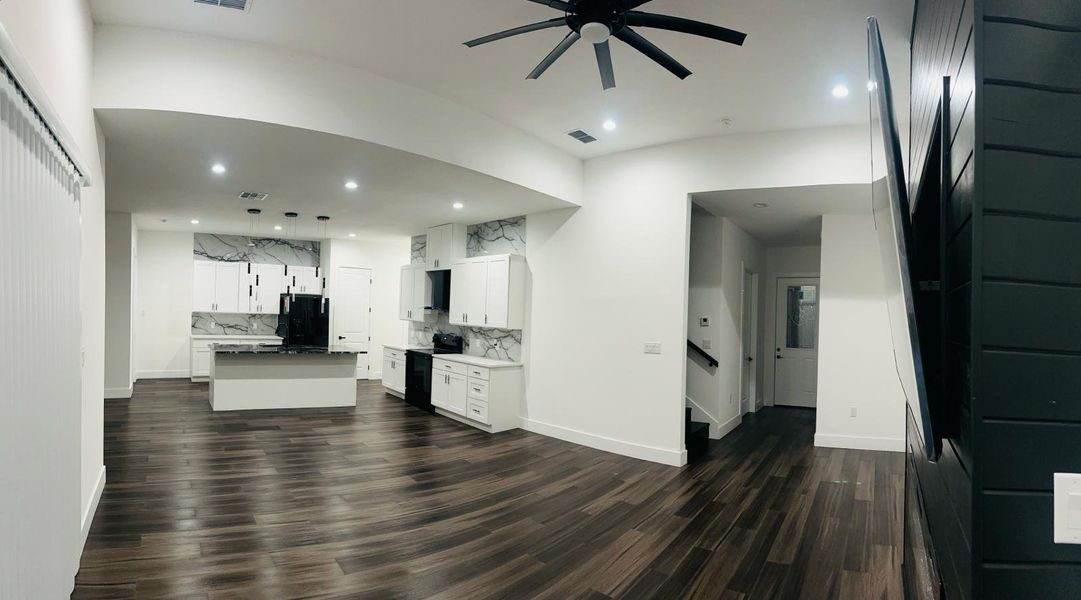 Kitchen with a center island with sink, ceiling fan, black appliances, dark wood finished floors, and white cabinetry Kitchen with a center island with sink, ceiling fan, black appliances, dark wood finished floors, and white cabinetry