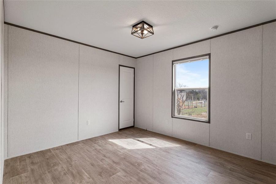 Unfurnished room with light wood-type flooring and ornamental molding