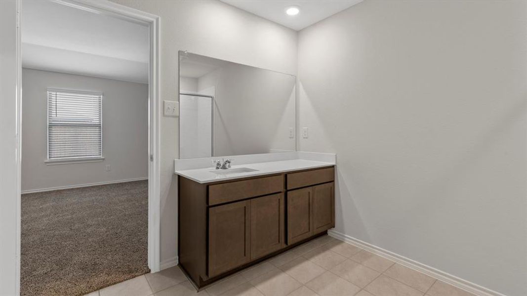Full bath featuring vanity, light colored carpet, a shower stall, and light tile patterned floors