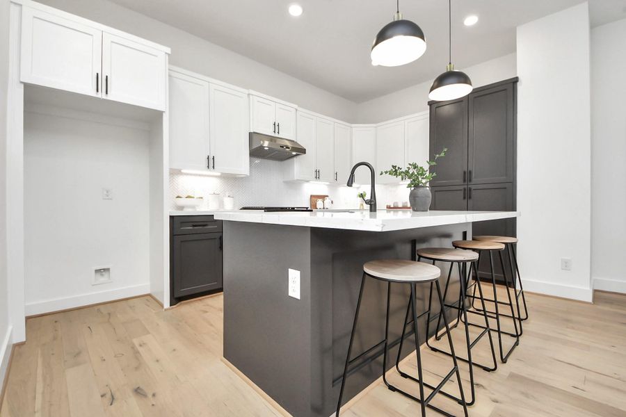 This modern kitchen features sleek white cabinets, a large black island with a marble countertop, and stylish pendant lighting. The space includes bar seating and has light wood flooring for a bright, contemporary feel. This modern kitchen features sleek white cabinets, a large black island with a marble countertop, and stylish pendant lighting. The space includes bar seating and has light wood flooring for a bright, contemporary feel.
