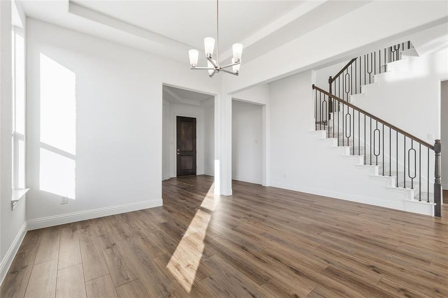 Unfurnished dining area featuring suspended lighting, dark wood-style floors, and a raised ceiling Unfurnished dining area featuring suspended lighting, dark wood-style floors, and a raised ceiling