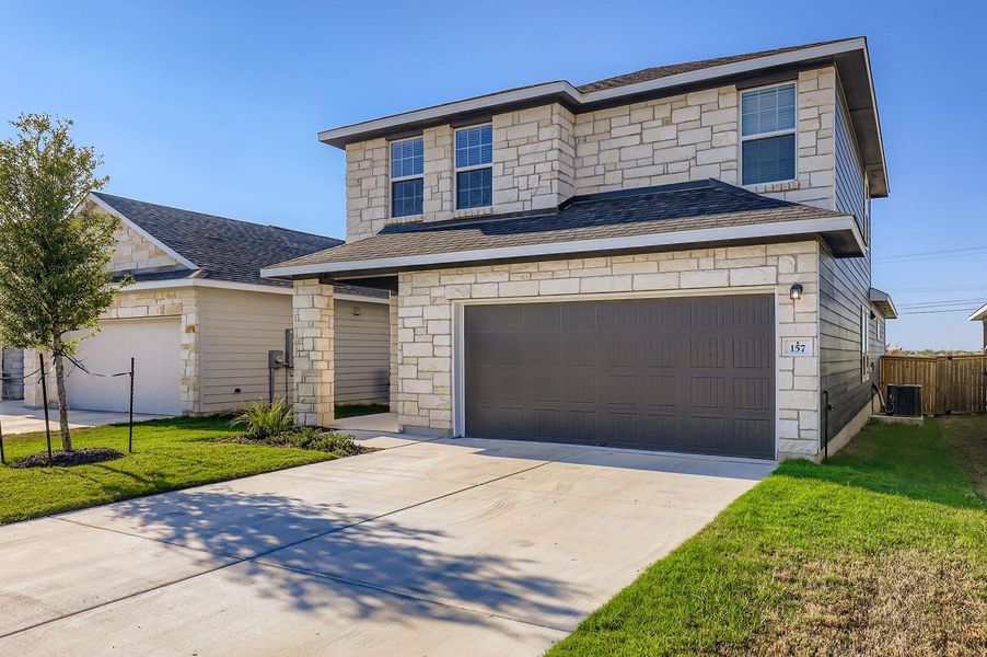 View of front of home with roof with shingles, concrete driveway, and stone siding