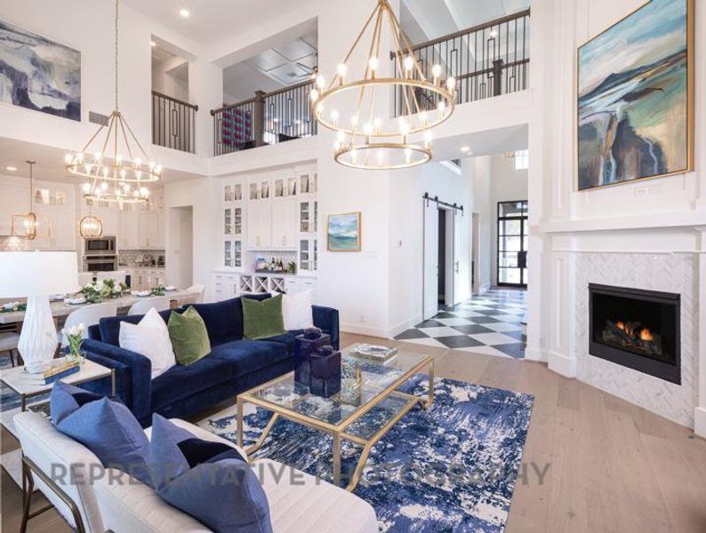 Living area with a notable chandelier, baseboards, wood finished floors, a fireplace, and a high ceiling Living area with a notable chandelier, baseboards, wood finished floors, a fireplace, and a high ceiling