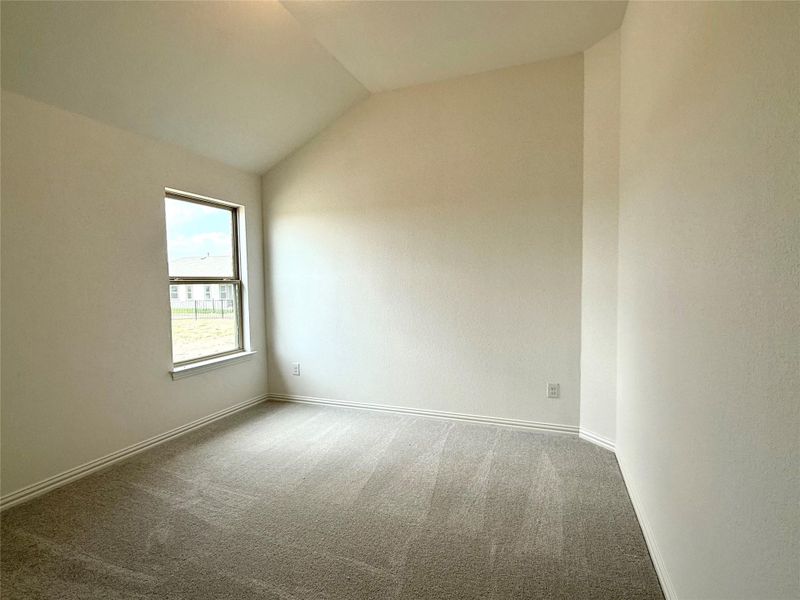 Carpeted empty room with vaulted ceiling and baseboards Carpeted empty room with vaulted ceiling and baseboards