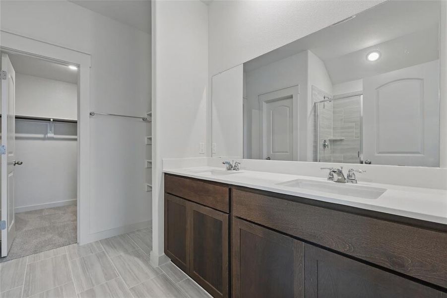 Full bathroom with double vanity, a shower stall, and a spacious closet Full bathroom with double vanity, a shower stall, and a spacious closet