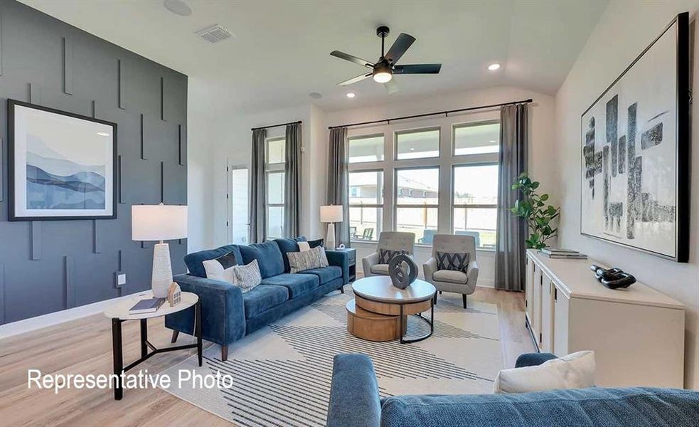 Spacious living area featuring a vaulted ceiling with a ceiling fan, recessed lighting, and large windows with transom elements