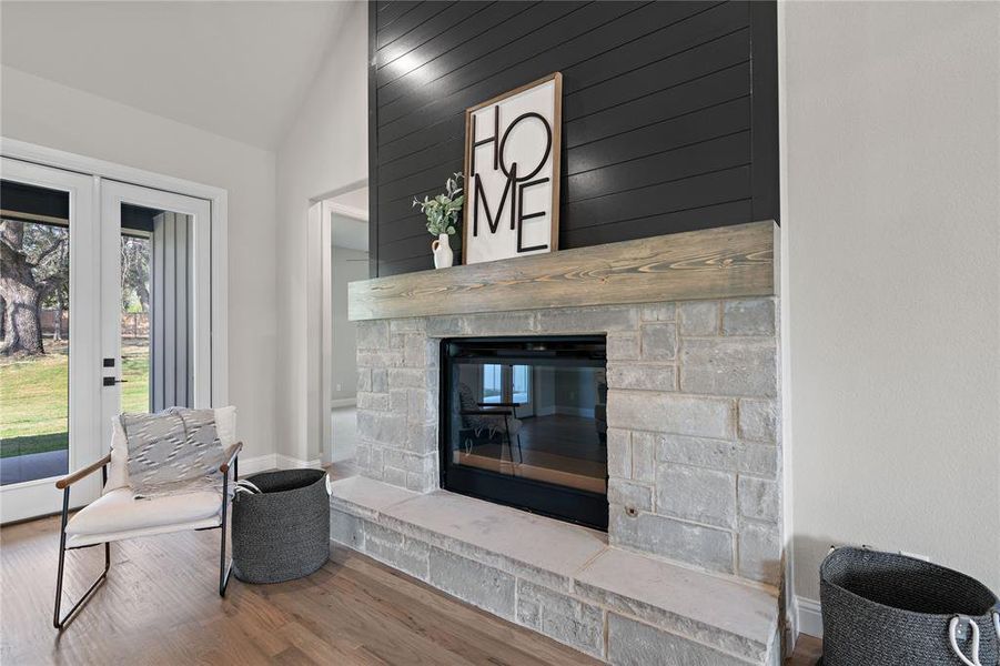 Living area with lofted ceiling, a stone fireplace, and hardwood / wood-style flooring