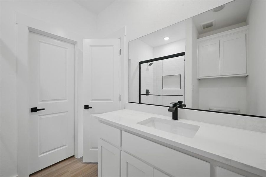Full bath with vanity, an enclosed shower, wood finished floors, toilet, and recessed lighting