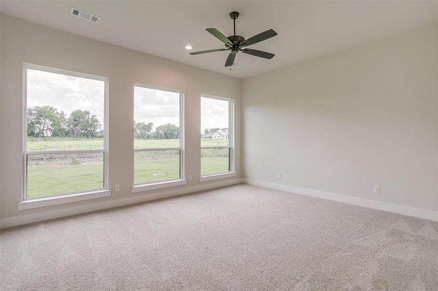 Carpeted empty room with a healthy amount of sunlight and ceiling fan