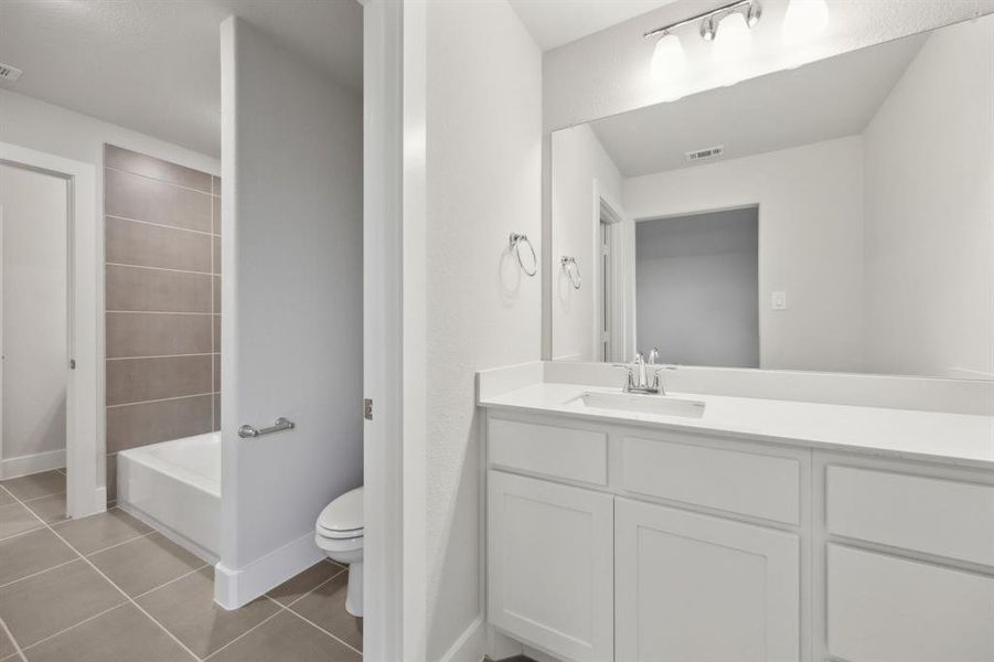 Full bathroom with tile patterned flooring, vanity, shower / washtub combination, and toilet