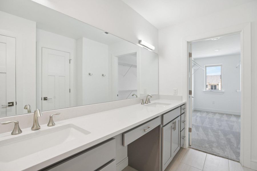 Bathroom featuring double vanity, light carpet, and light tile patterned floors