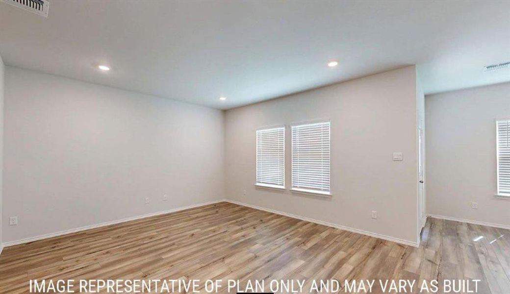 Spacious room featuring wood-finish flooring, recessed lighting, and multiple windows with blinds Spacious room featuring wood-finish flooring, recessed lighting, and multiple windows with blinds