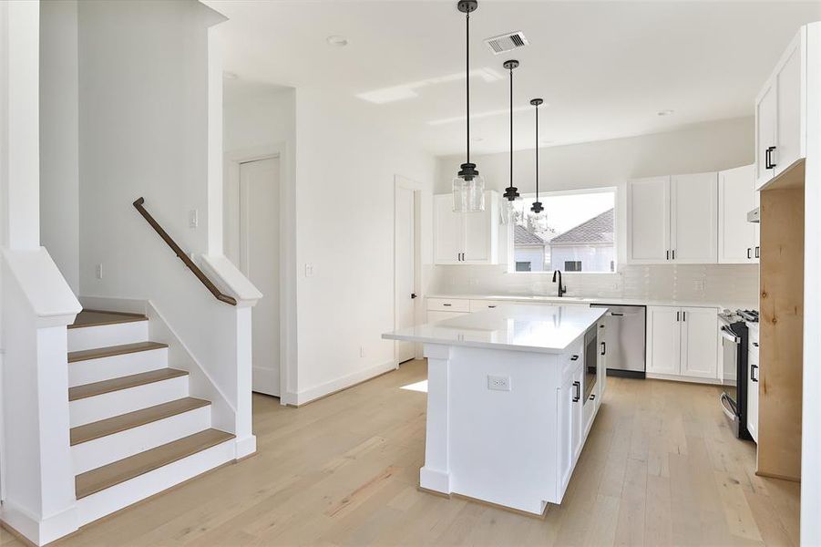 A spacious walk-in pantry tucked in the corner of this charming kitchen, with a convenient powder room for guests to the left.