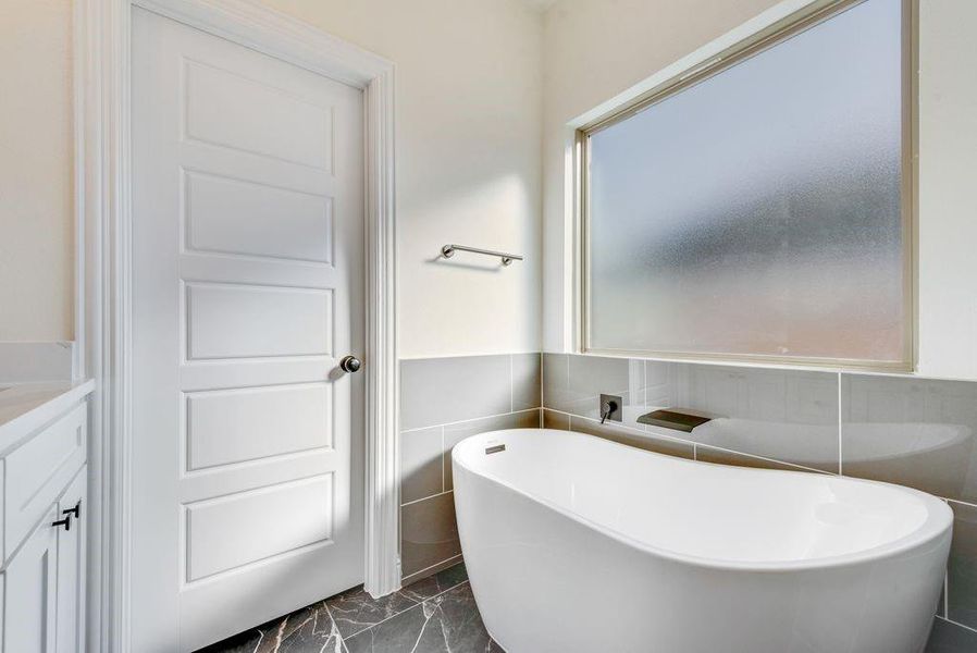 Owner's Bathroom featuring vanity, tile walls, and a washtub