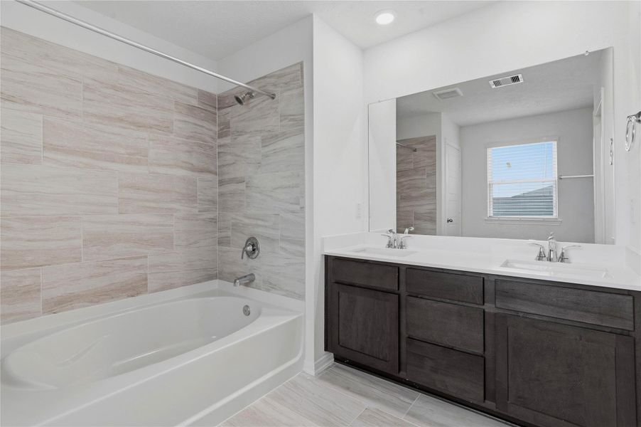 This stunning primary bathroom is truly move-in ready! It features stained cabinetry with light countertops, dual sinks, a large mirror, high ceilings, custom paint, a large window, and sleek modern finishes throughout.