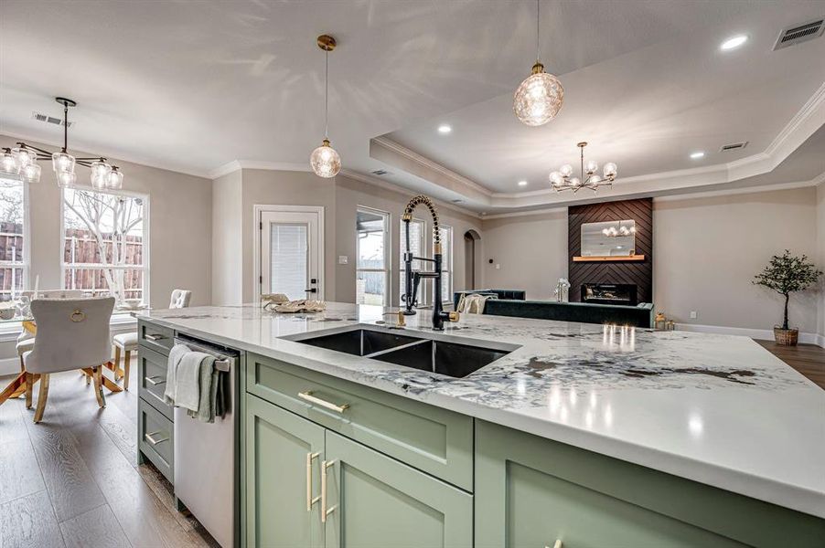 Kitchen with sink, a tray ceiling, light stone countertops, and green cabinets