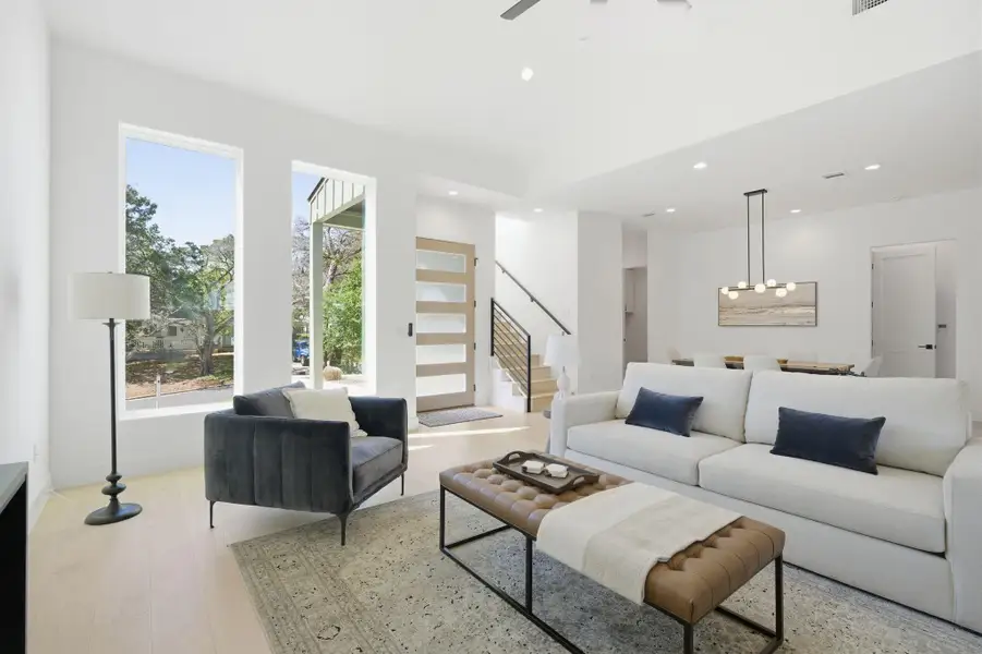Living room with light wood-style floors, ceiling fan, and hanging lights