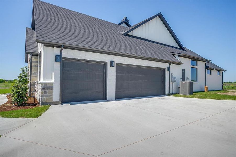 View of side of home with roof with shingles, driveway, central AC unit, and an attached garage View of side of home with roof with shingles, driveway, central AC unit, and an attached garage