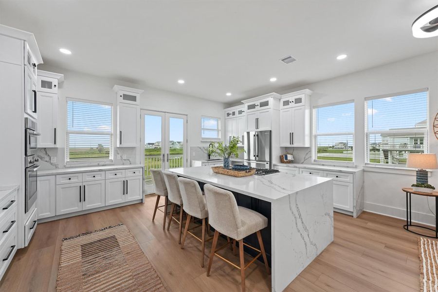 Gorgeous waterfall-edge quartz island, gas range, custom cabinetry, and designer lighting elevate the chef’s kitchen to a true showpiece. Gorgeous waterfall-edge quartz island, gas range, custom cabinetry, and designer lighting elevate the chef’s kitchen to a true showpiece.