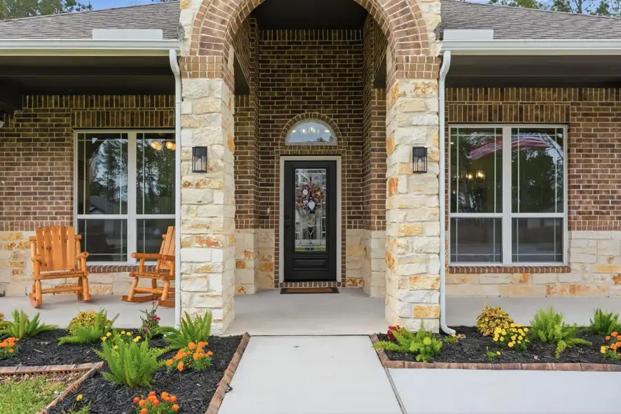 Inviting covered front porch with stone accents and a charming entryway.