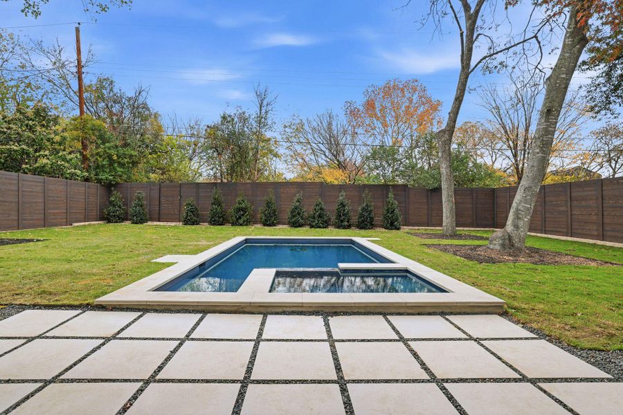 View of swimming pool featuring a fenced backyard, a patio area, and a pool with connected hot tub