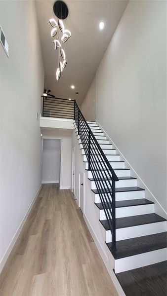 Stairs featuring baseboards, wood finished floors, visible vents, and recessed lighting