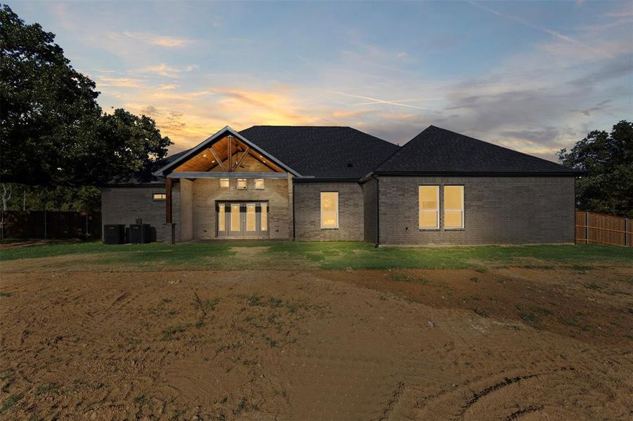 View of front facade featuring brick siding, french doors, and a shingled roof