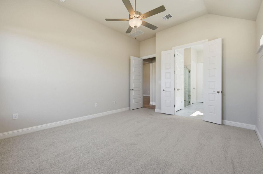 Unfurnished bedroom with light carpet, a ceiling fan, ensuite bathroom, and lofted ceiling Unfurnished bedroom with light carpet, a ceiling fan, ensuite bathroom, and lofted ceiling