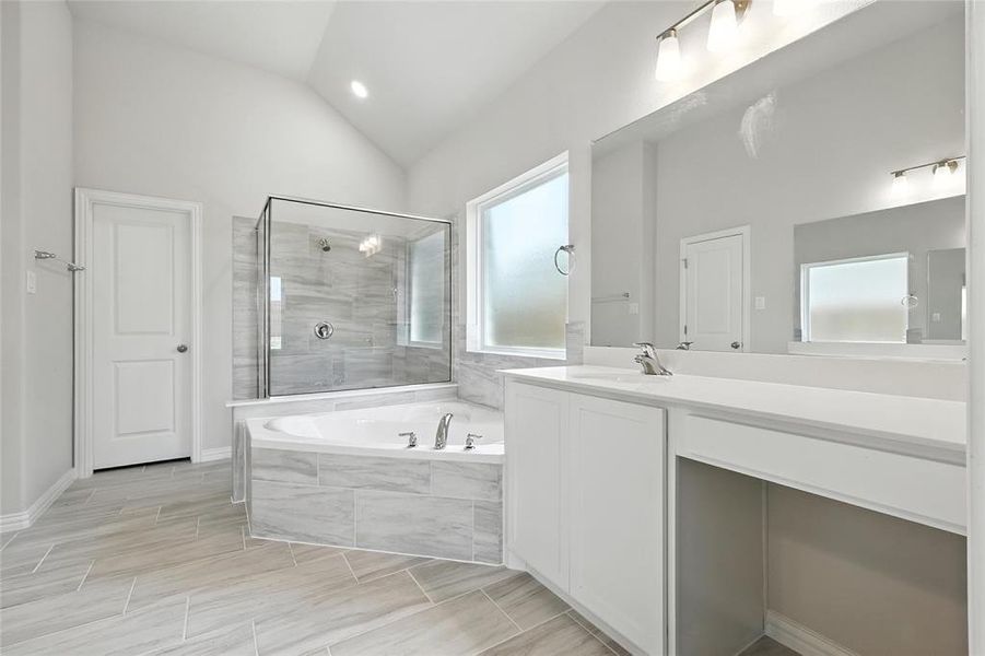Bathroom with a stall shower, lofted ceiling, vanity, a bath, and recessed lighting