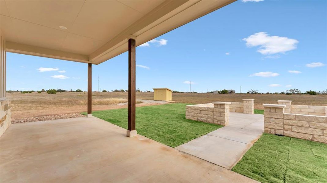 An inviting covered patio opens up to stone retaining walls and far-reaching sky views. An inviting covered patio opens up to stone retaining walls and far-reaching sky views.